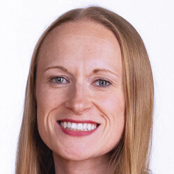 A woman with straight, light brown hair and blue eyes smiles at the camera against a plain white background.