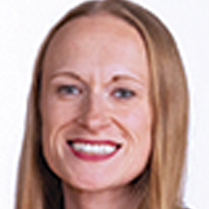 A woman with straight, light brown hair, fair skin, and red lipstick smiles at the camera against a plain white background.