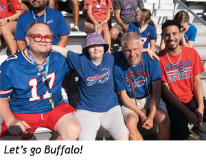 Four people in Buffalo Bills apparel sitting together in stadium bleachers.