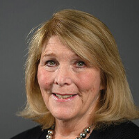 Portrait of a middle-aged woman with shoulder-length blonde hair smiling at the camera.
