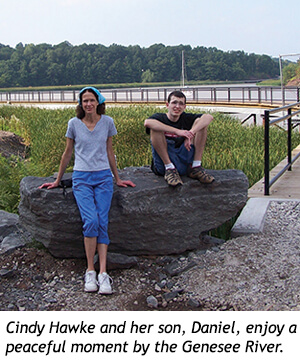 Cindy Hawke and her son, Daniel, sit on a large rock along the Genesee River.