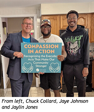 Three men stand together holding a sign that reads, Compassion in Action: Recognizing the Everyday Acts That Make Our Community Stronger.