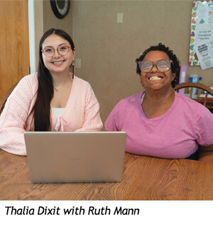 Thalia Dixit and Ruth Mann sitting at a wooden table with a laptop for the Fall 2026 Spirit Newsletter.