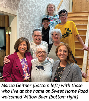 Marisa Geitner and Willow Baer pose with a group of seven residents on a staircase.